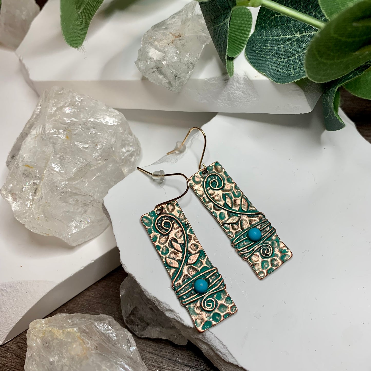 Beautiful pair of hammered copper earrings with turqoise wisps throughout and a synthetic turqoise stone. with the clasp they hang about 2 inches long and are about 1 half inch wide.