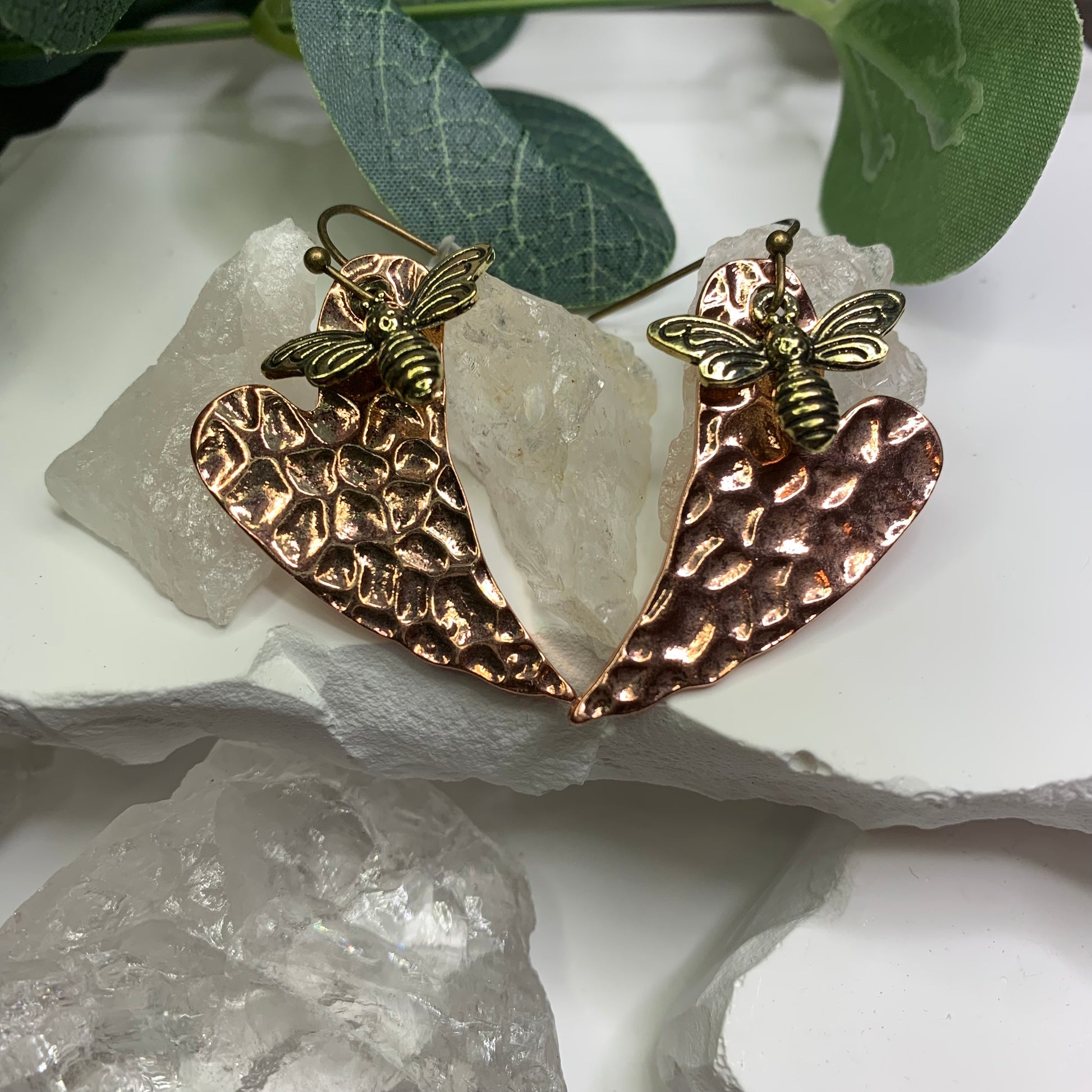 1.5 inch beautiful Hammered copper dangle earrings with golden bumble bee charm displayed beautifully with a white background on crystals and greenery