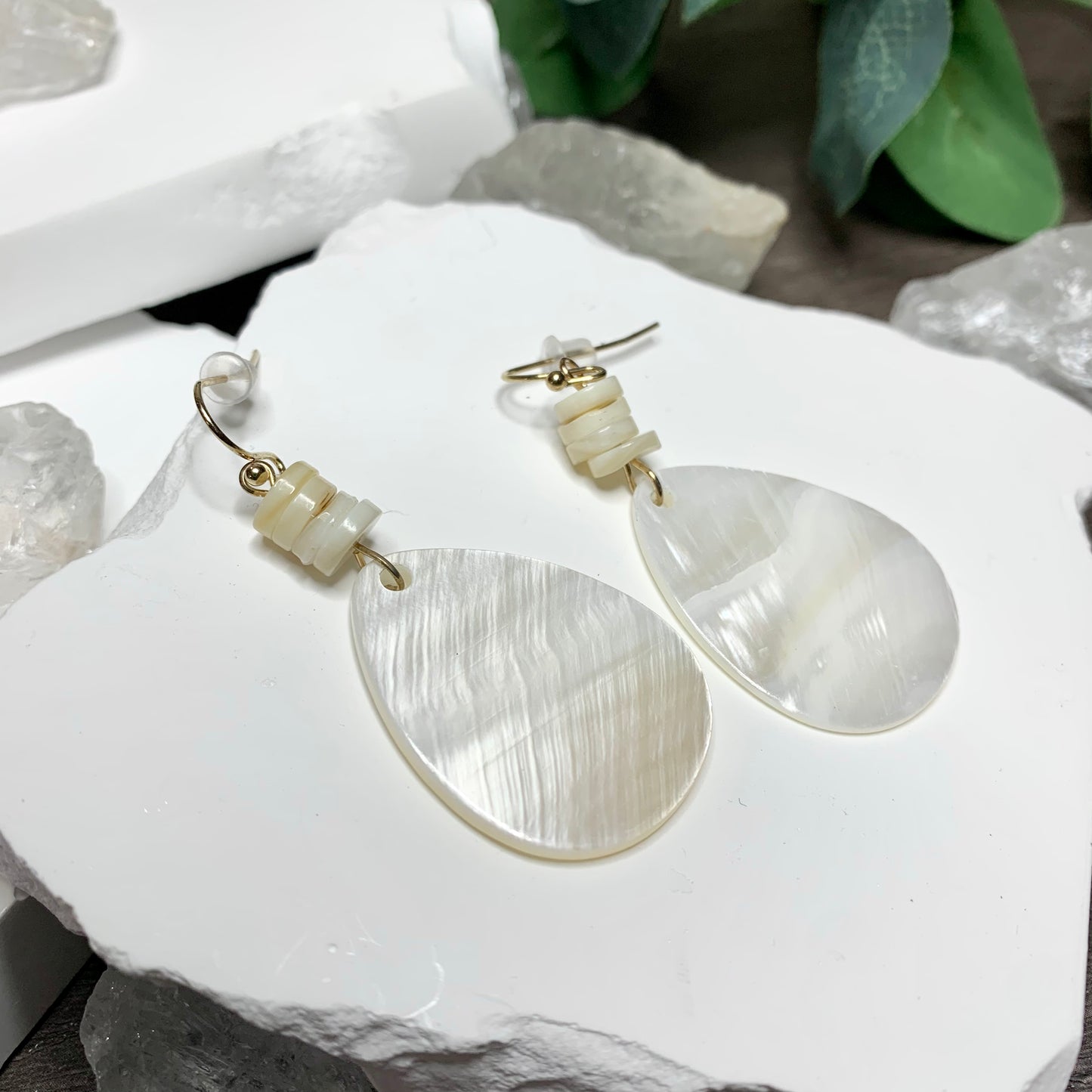 beautiful mother of pearl dangle earrings in a teardrop shape. Has 4 round carved shell beads and gold hook