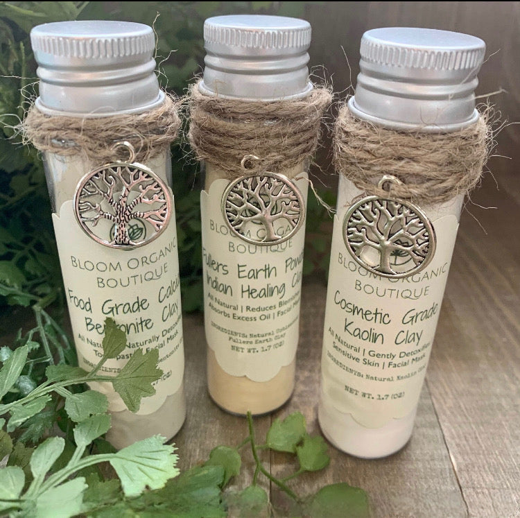 Wooden background with green leaves displaying a gift set of 3 lovely clays to sample. Each in a 1.7 oz recyclable plastic tube container. You receive Calcium Bentonite Food Grade Clay, Fullers Earth Indian Healing Clay & Kaolin Cosmetic Grade Clay.